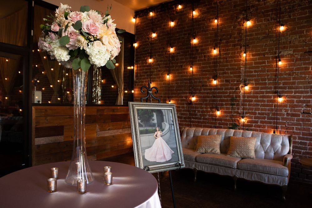 Elegant floral centerpiece with string lights and exposed brick wall backdrop.
