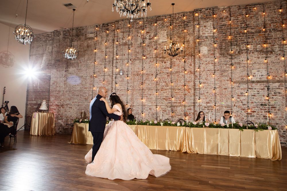 Reception dance with crystal chandeliers and romantic lighting in rustic brick venue.