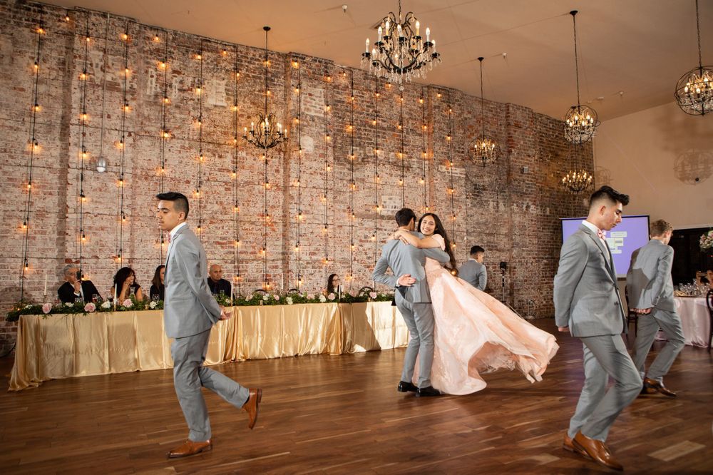Festive dance celebration in elegant ballroom with crystal chandeliers and brick walls.