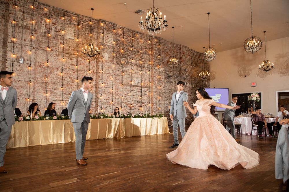 Reception dance party in rustic venue with crystal chandeliers and exposed brick walls.