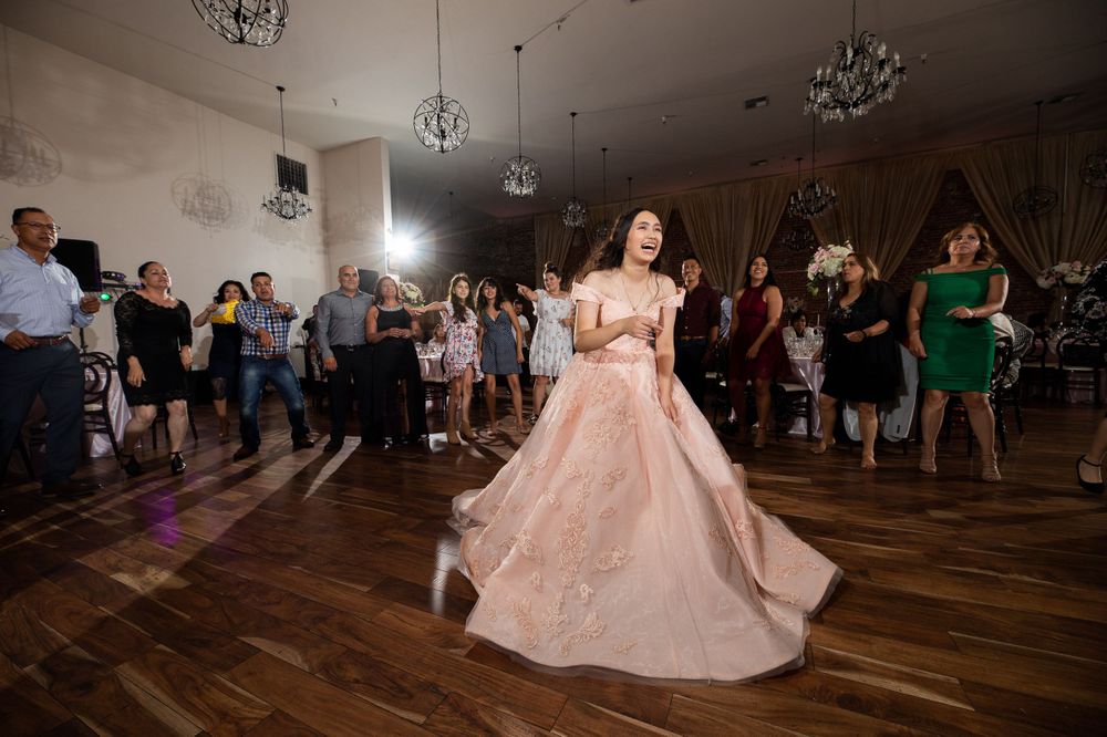 A flowing pink princess gown spins gracefully on a wooden dance floor under crystal chandeliers.