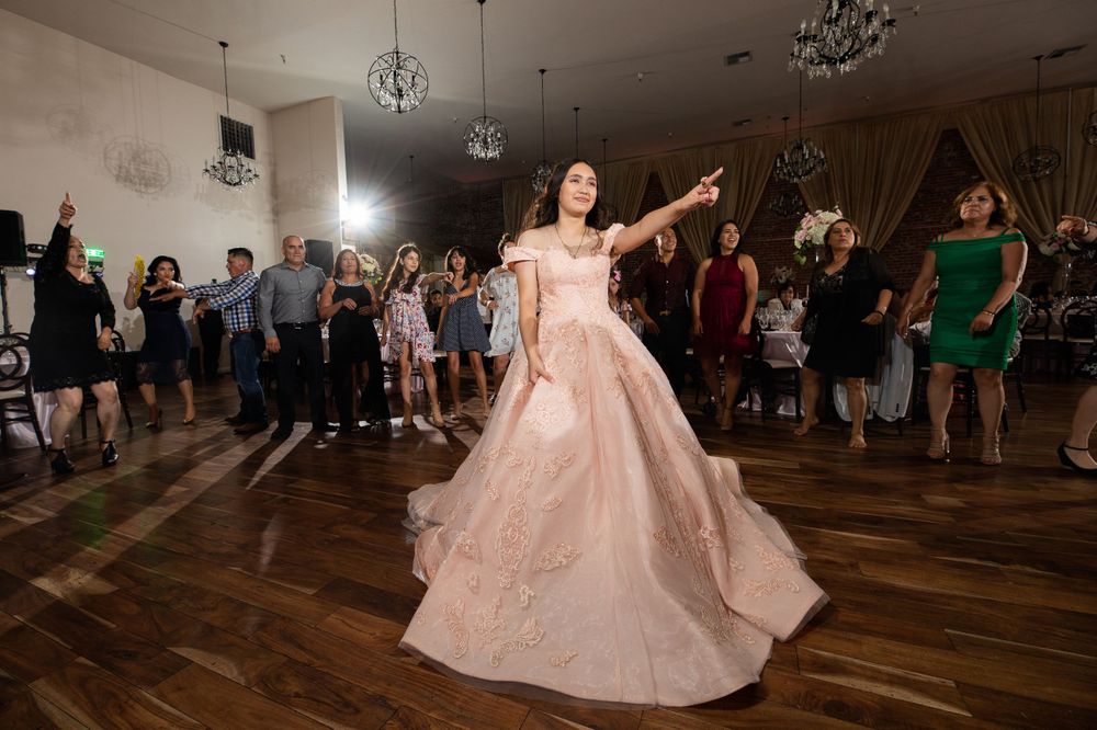 A festive dance party features a pink ballgown at center while guests dance and celebrate.