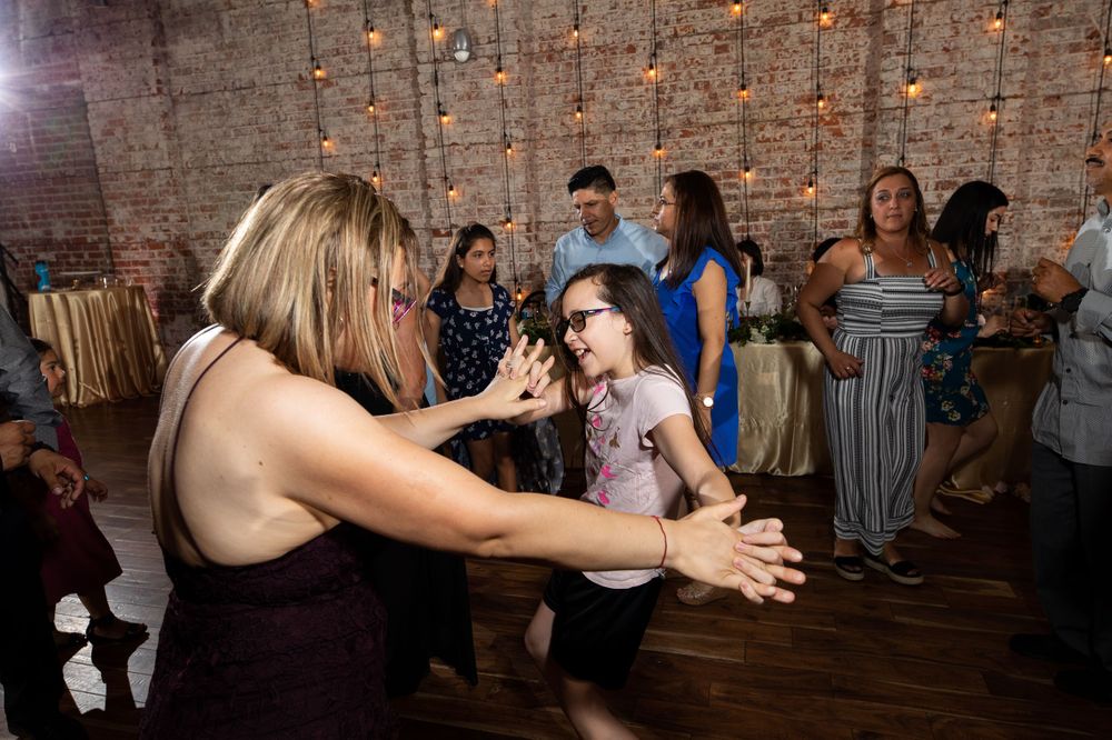 Energetic dancers enjoy themselves on a wooden floor at an indoor celebration.