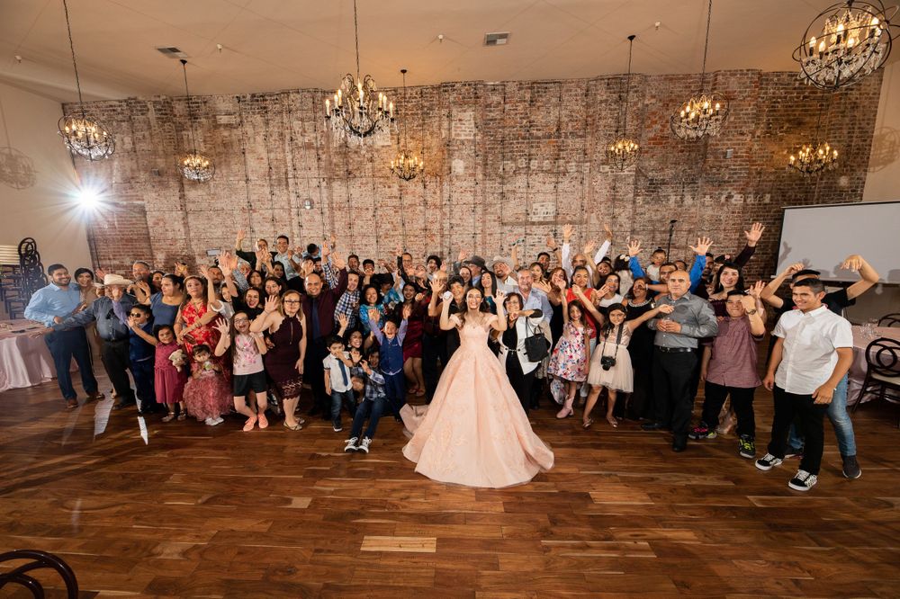 Large wedding party group photo with everyone celebrating in a rustic indoor venue.