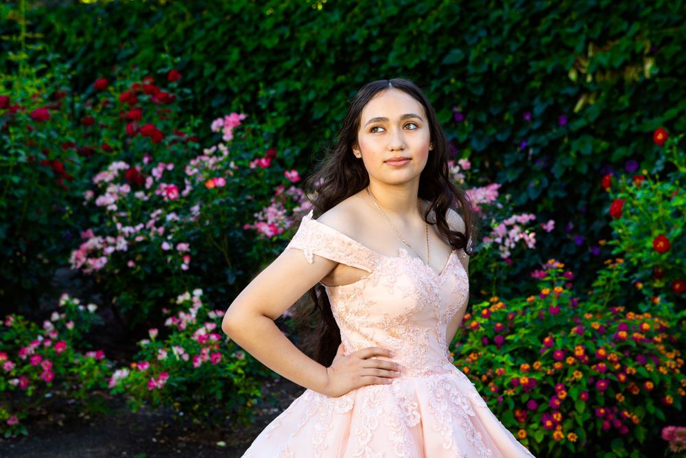 Formal pink dress portrait among colorful garden flowers.