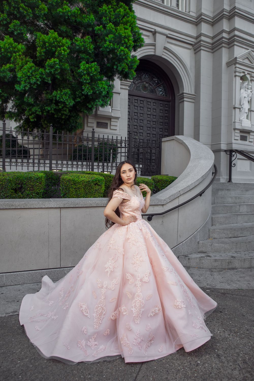 Pink ballgown dress photographed at classic architectural entrance with stone steps.