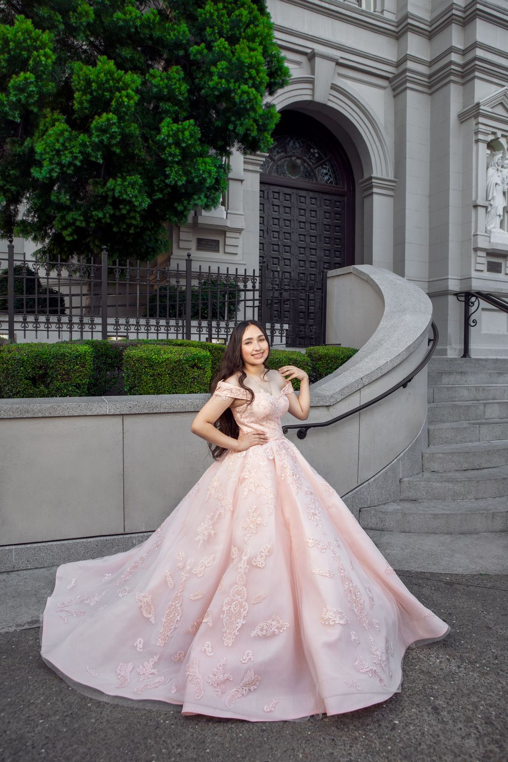 Pink embellished ballgown showcased against ornate architectural backdrop.