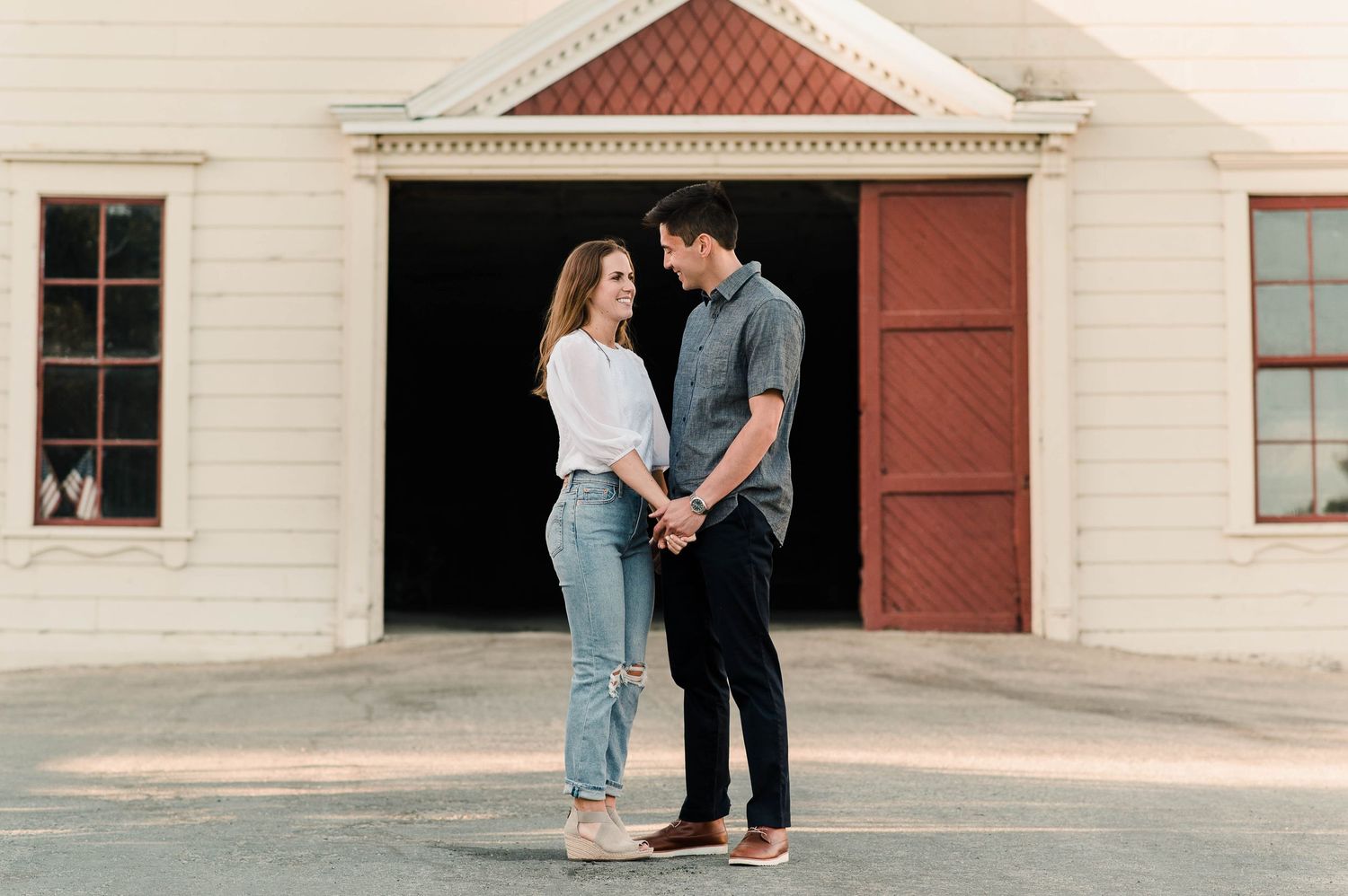 A tender moment shared between two people standing in front of a rustic barn door entrance.