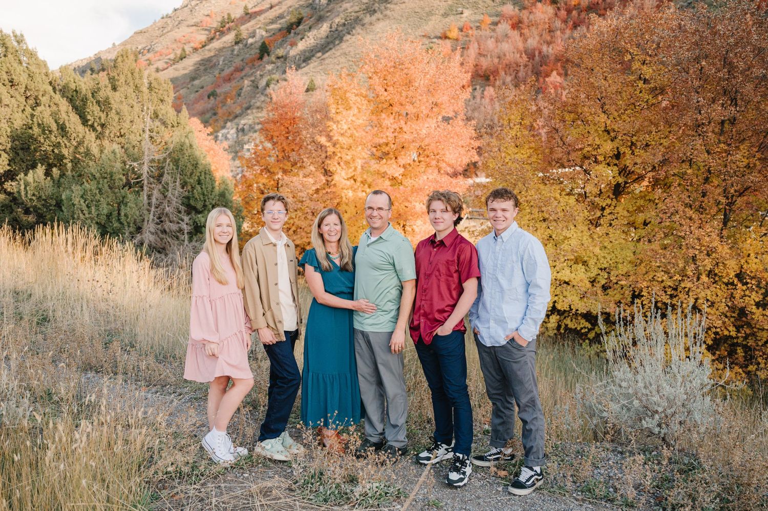 A group poses for a family portrait against beautiful fall foliage and mountain scenery.