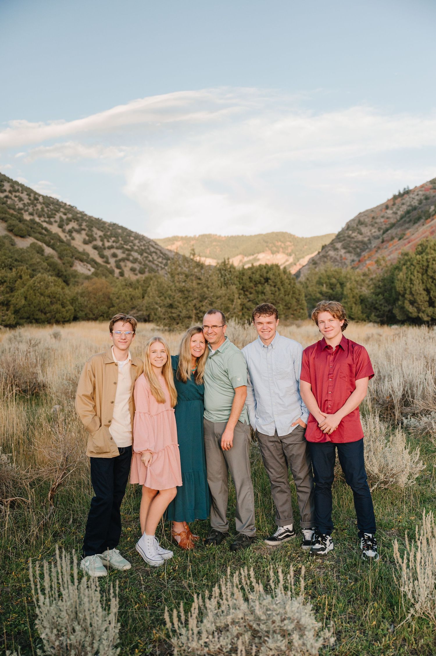 Family group poses in a mountain valley with sage brush and clear blue skies.