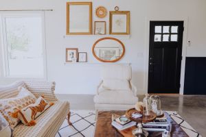 Bright living room with vintage frames arranged on white wall and comfortable seating area.