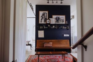 Modern living room with dark accent wall featuring vintage photographs and a red patterned rug.