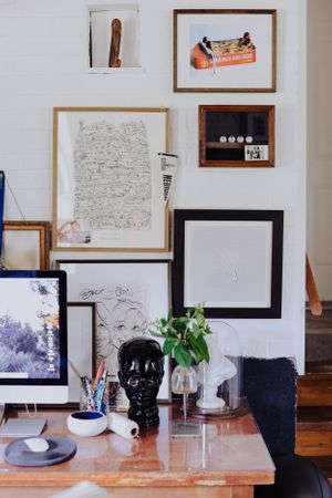 Gallery wall featuring various artworks and sketches above a wooden table with decorative objects.