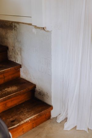 Wooden staircase with white walls showing signs of age and wear.