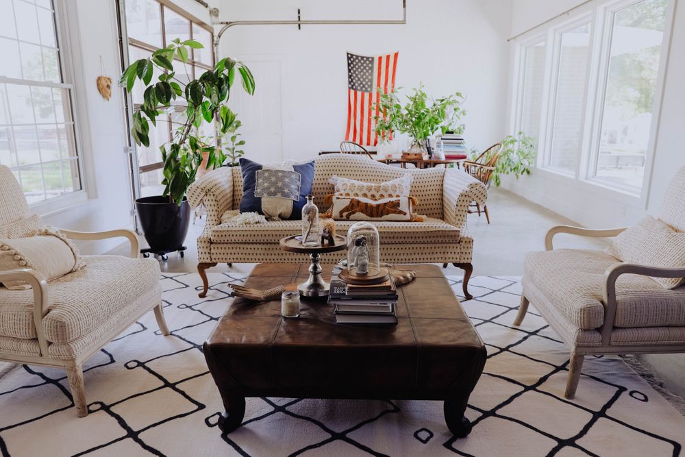 Airy living space with large windows, indoor plants, and neutral-toned furniture.