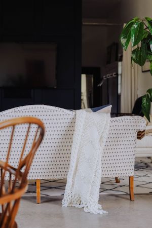 Row of white cushioned chairs with decorative throw blankets in a bright interior space.