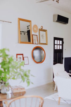 Modern living room with wooden frames and mirrors on white walls.