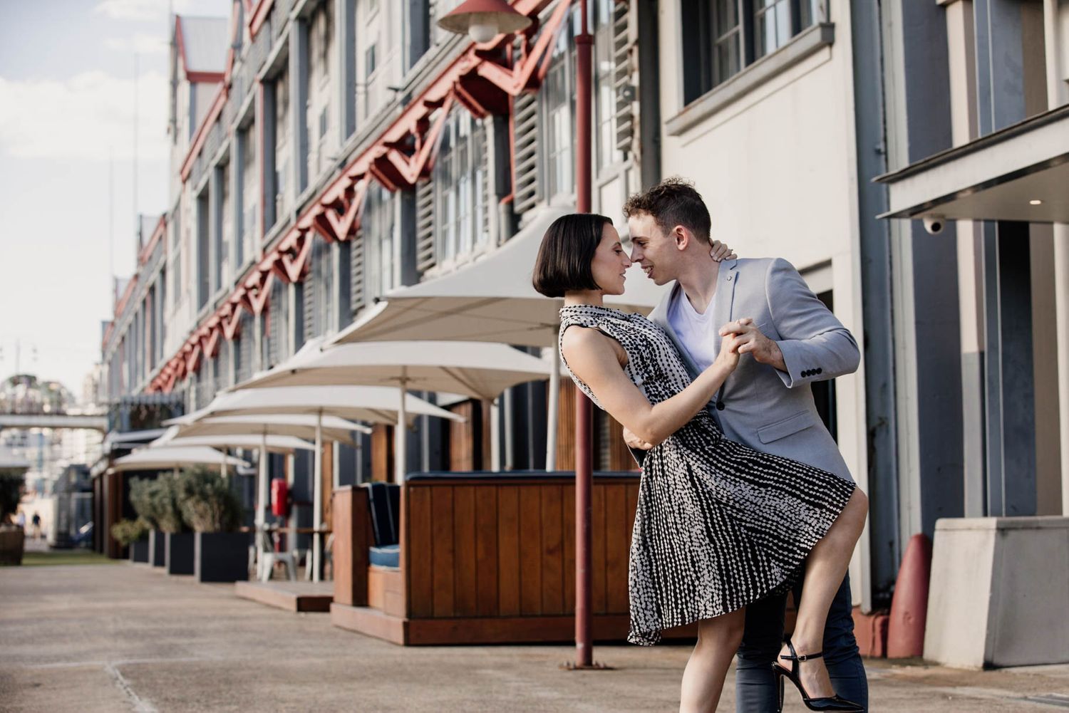 A romantic dance sequence on a city sidewalk with vintage storefronts in the background.