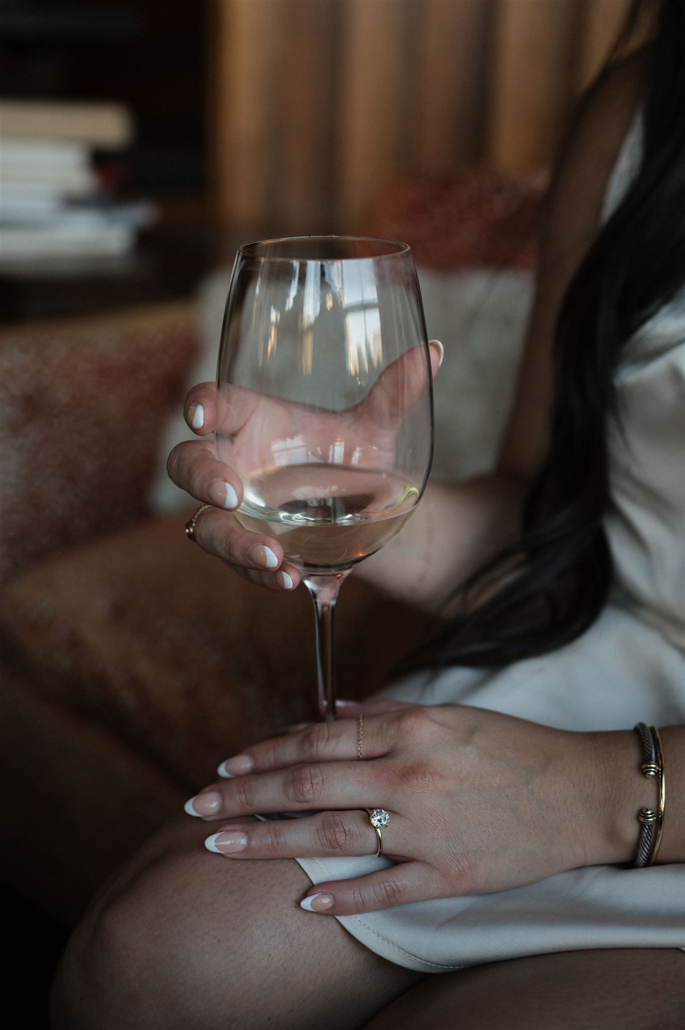 Close-up of hands holding a wine glass with an engagement ring visible.