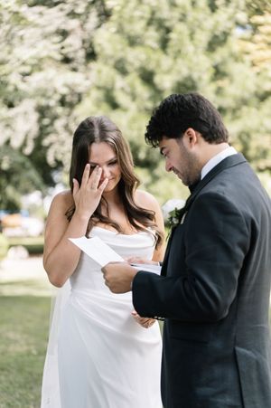 A couple shares an intimate moment in a park setting with the woman in white and man in dark suit.