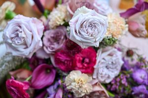 Close-up of elegant purple and pink bridal bouquet featuring roses and mixed blooms.