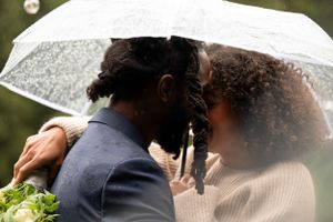 Close-up of couple sharing tender moment under clear umbrella in the rain.