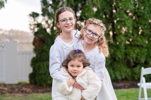 Three young flower girls in white dresses posing together outdoors at a Baltimore intimate wedding.