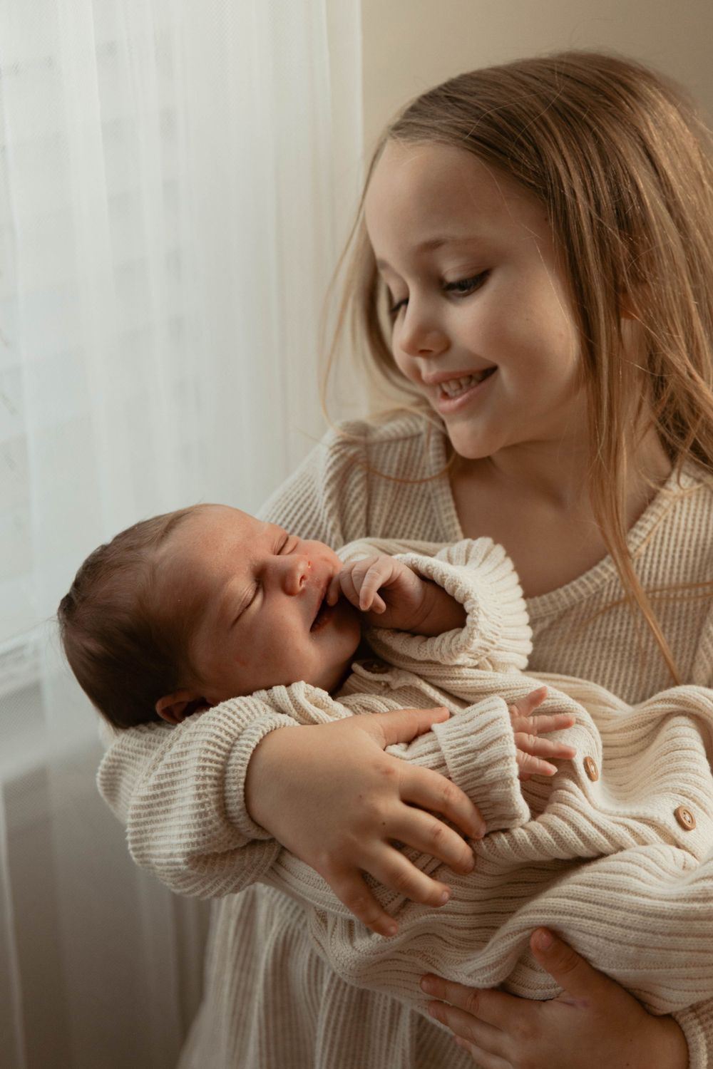 Parent shares intimate bonding moments with newborn baby in soft natural light.