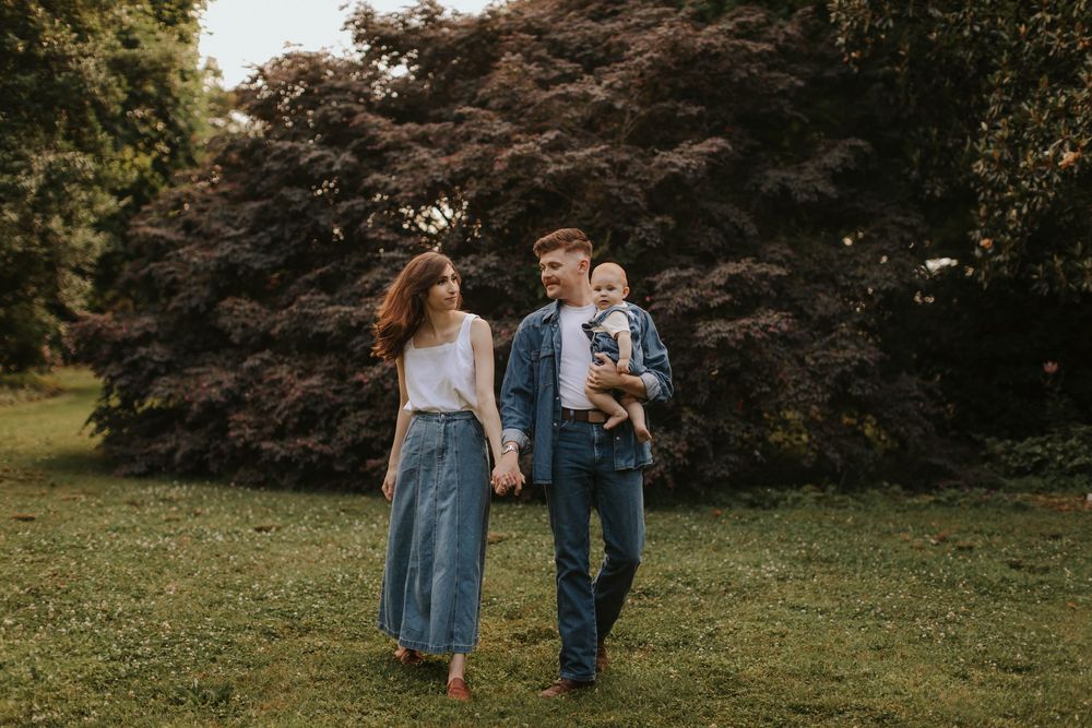 Family walking together through park with maple trees in background.