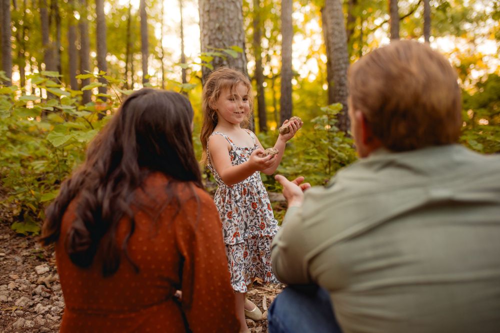 Family exploring the Mark Twain National Forest Pines in Missouri, with a little girl excitedly showing her parents a rock she found