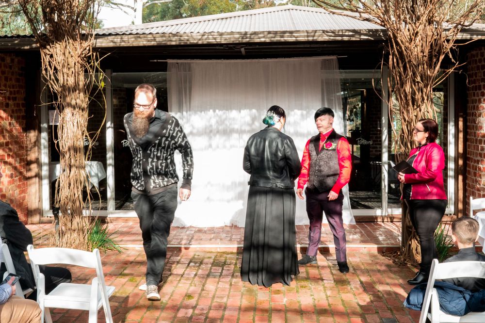 Wedding ceremony candid moment at brick-walled outdoor venue.
