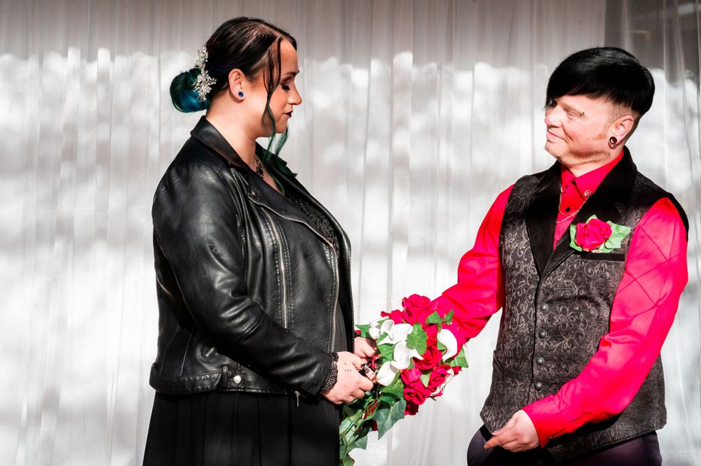 Alternative wedding couple exchanging flowers during ceremony.