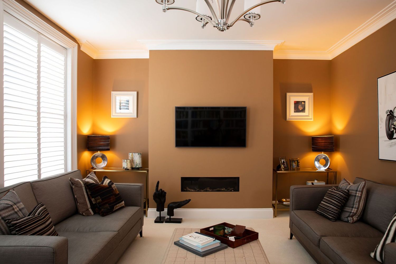 Contemporary living room with mounted TV, linear fireplace, and gray sofas against warm taupe walls.