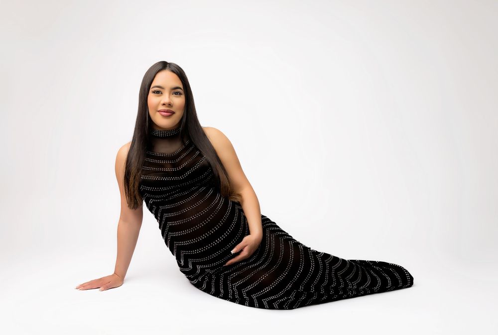 Person in striped black evening gown poses elegantly on white background.