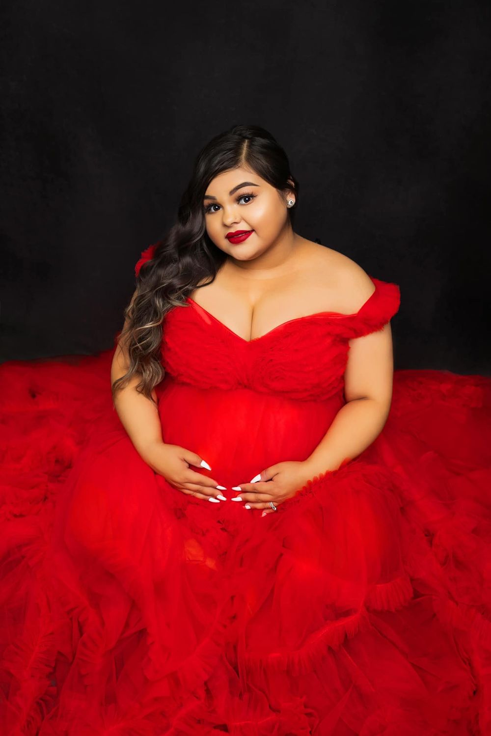 An elegant off-shoulder red gown with sweetheart neckline against dark backdrop.