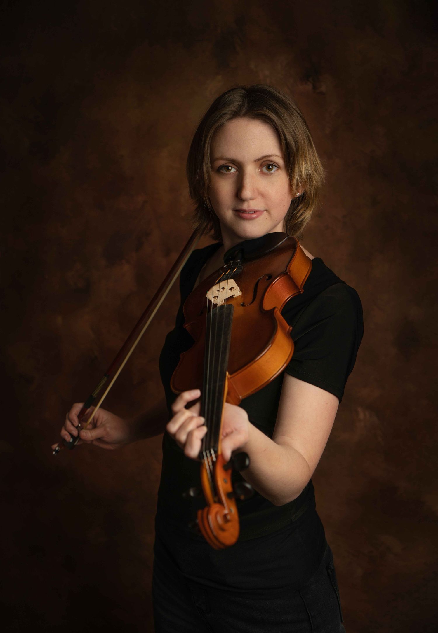 woman poses with violin in artistic headshot