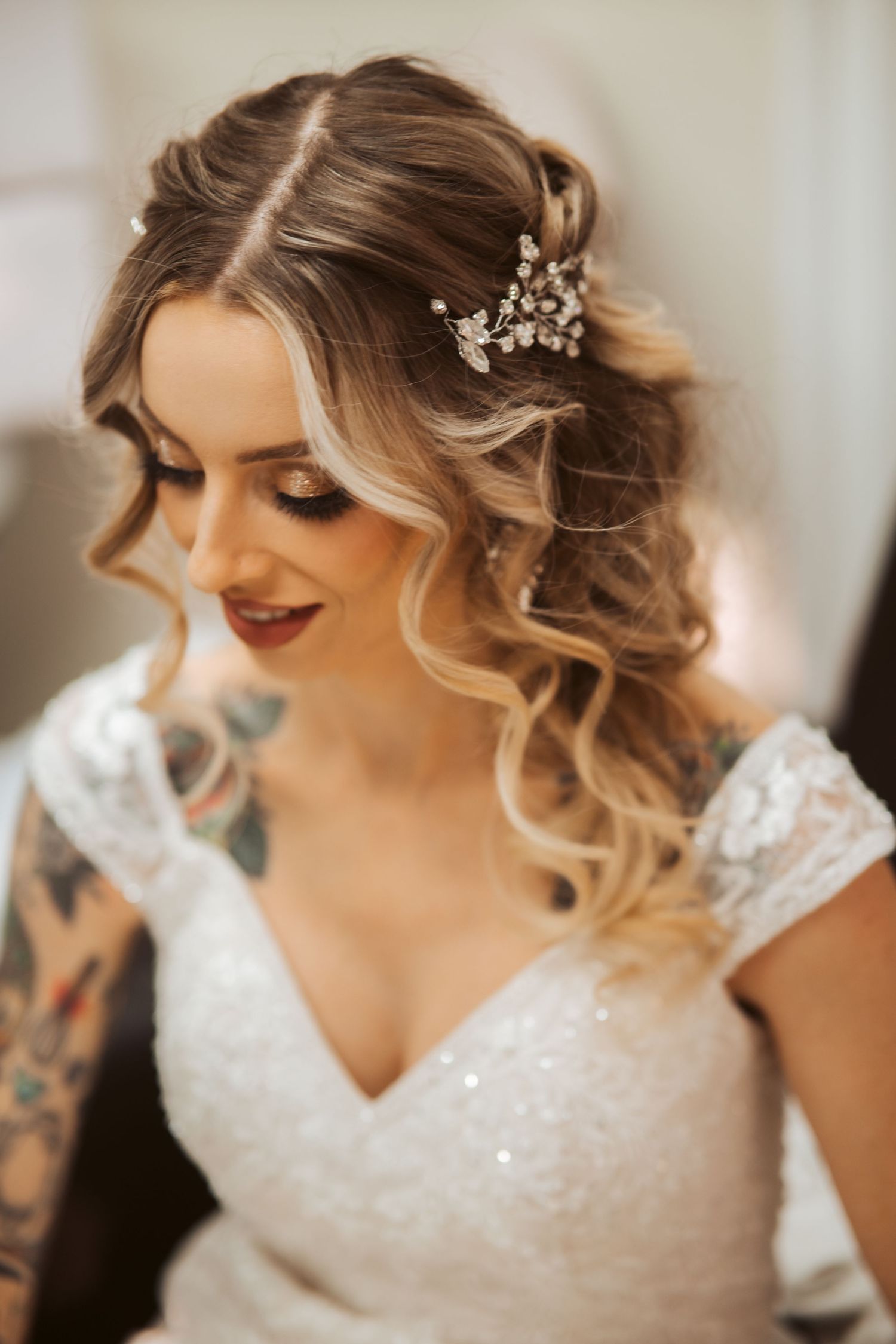 Close-up of elegant bridal hairstyle with curled blonde waves and crystal hair accessory.