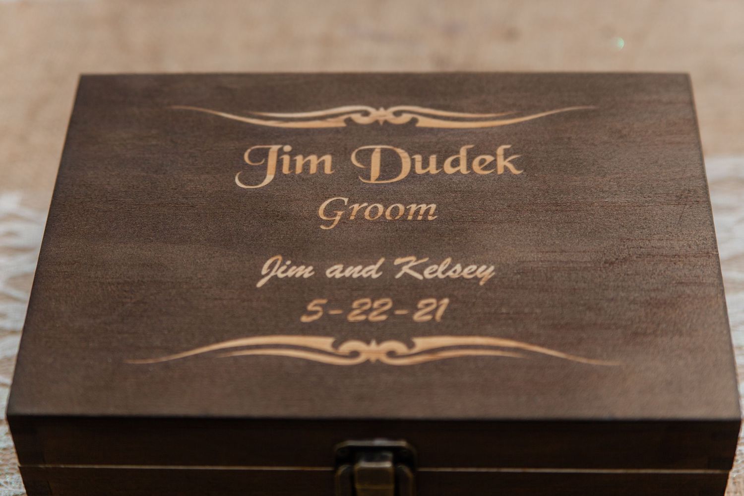 Wooden plaque with engraved names and decorative scrollwork for wedding signage.