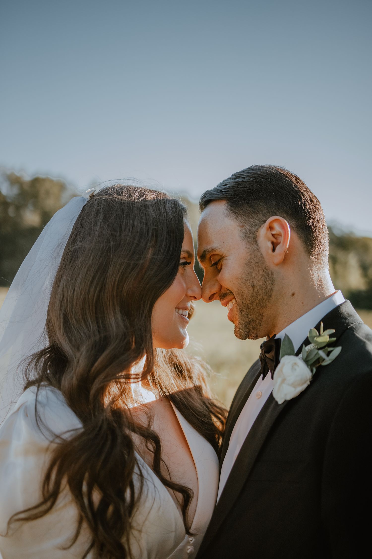 a bride and groom gaze into each other's eyes in the sun