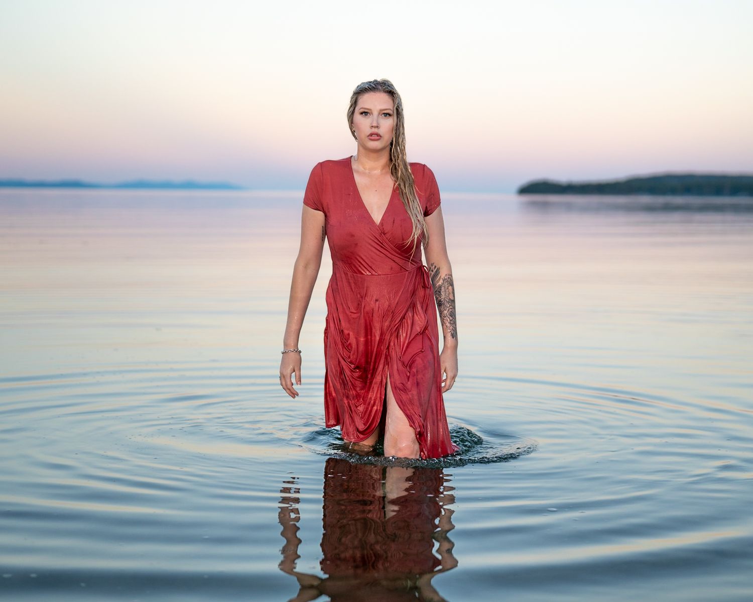 Soaking wet beautiful women walks out of the ocean in dress.
