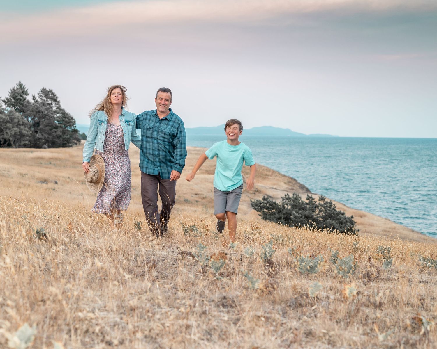 Couple with son walk hand in hand near the ocean.