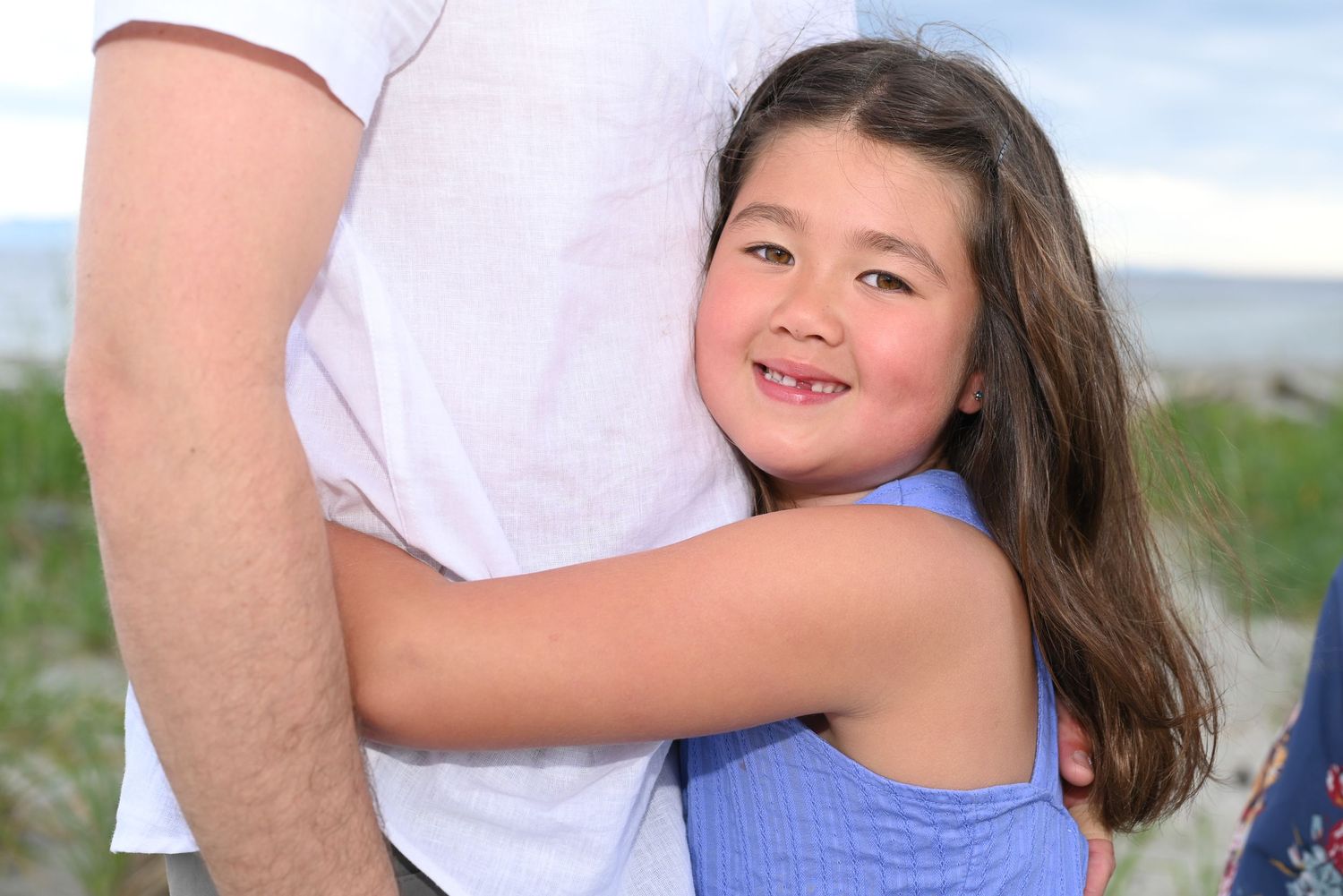 Photoshoot with young girl hugging her dad. Blue dress.