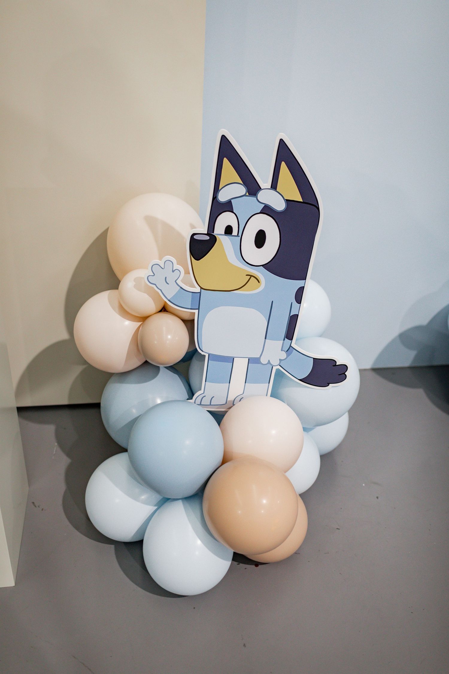 Cartoon dog character decoration with blue and beige balloon arrangement.