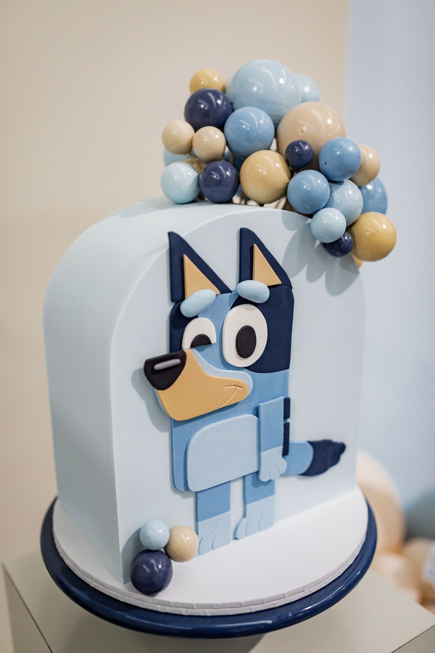 Blue and white fondant cake decorated with cartoon dog design and balloon garland.