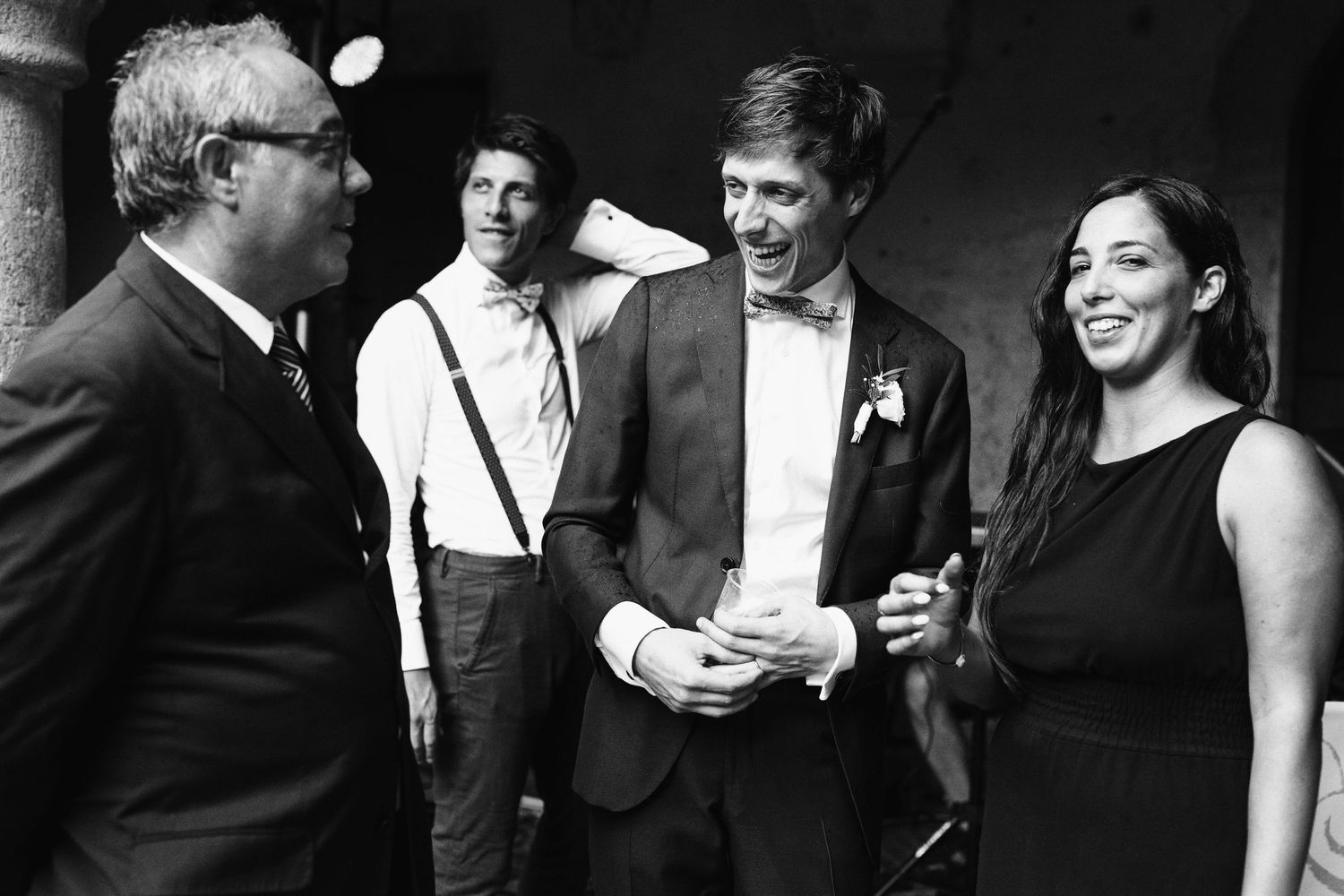Black and white candid shot of wedding guests conversing at a formal reception.