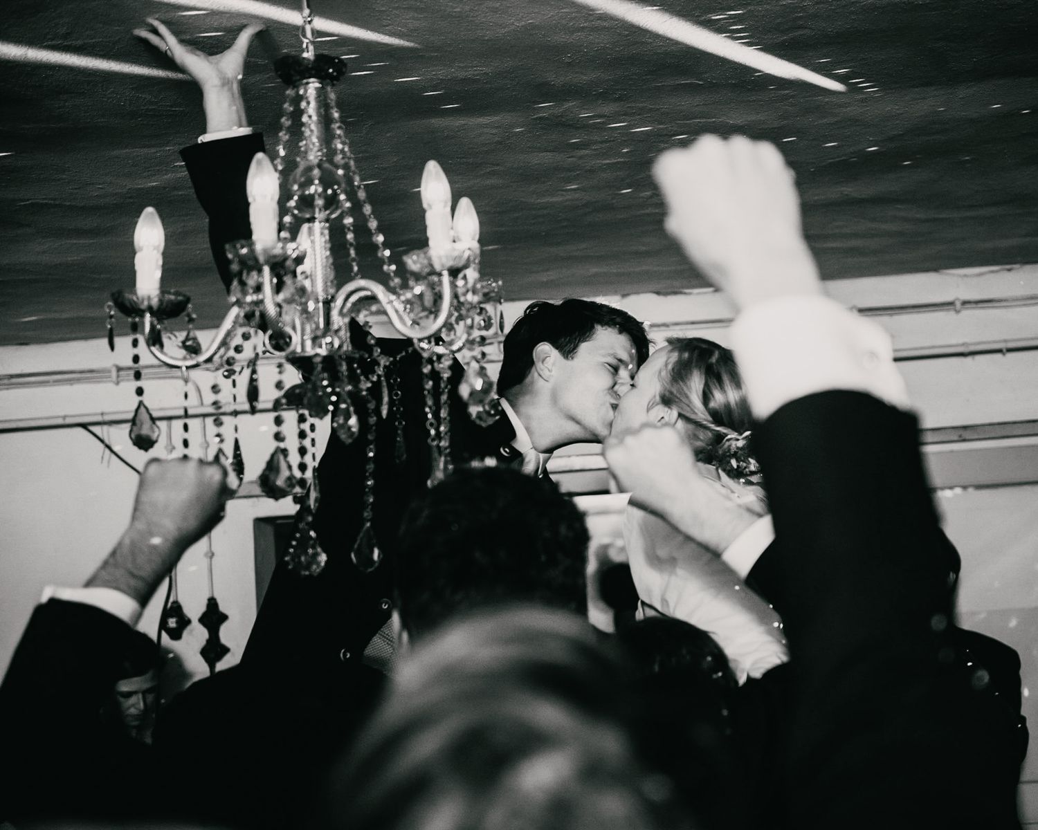 A romantic moment under a crystal chandelier at an elegant reception.