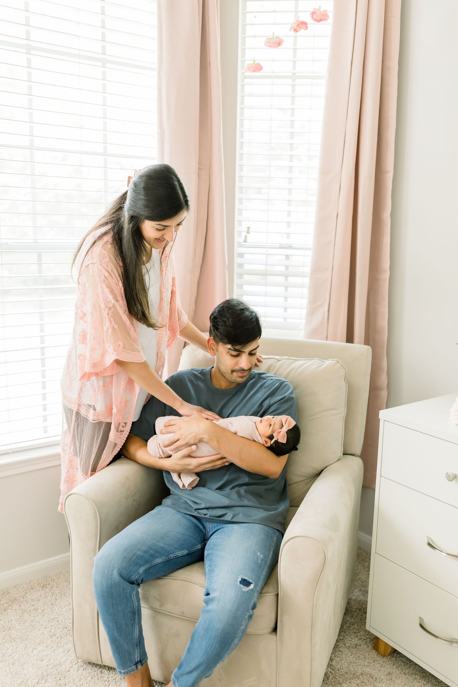 Young parents sharing a tender moment with their newborn baby in a nursery setting.