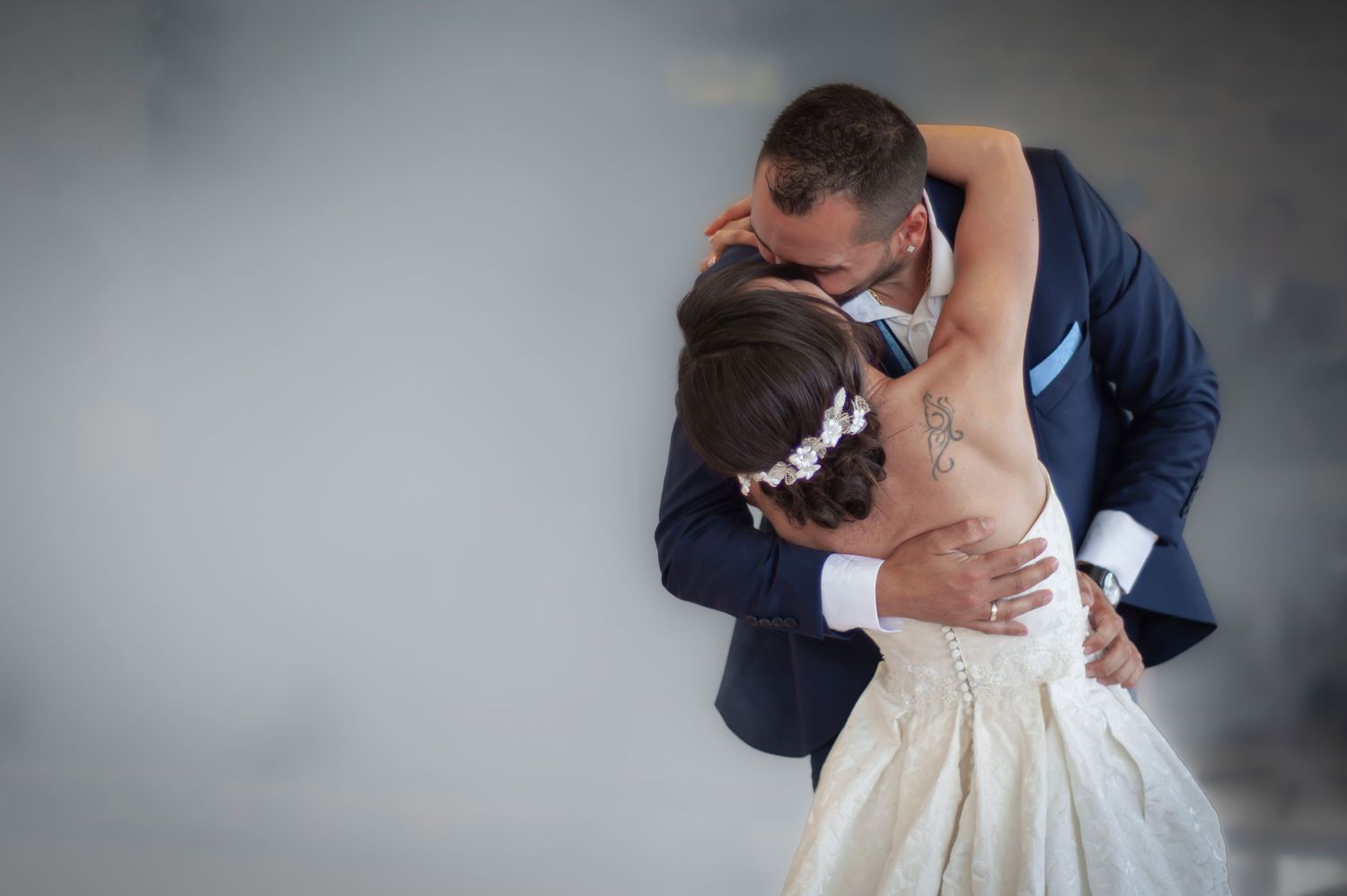Bride and groom share emotional first dance embrace in misty romantic wedding reception moment.
