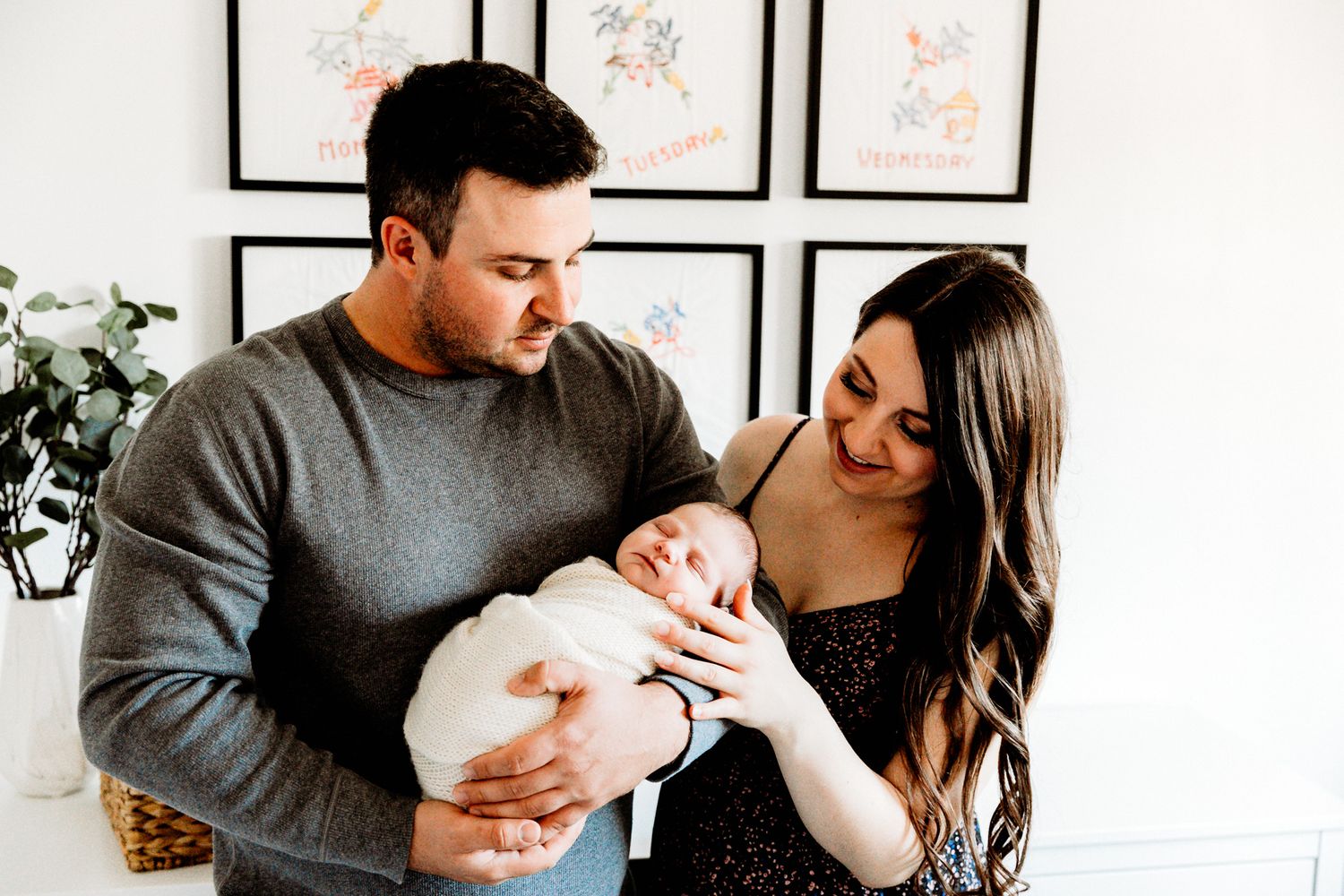 A couple lovingly gazes at their newborn baby in a bright nursery room.