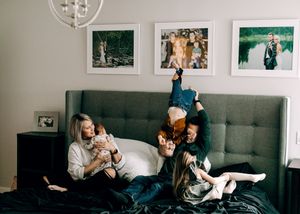 Family with children laughing and playing together on bed in cozy bedroom.